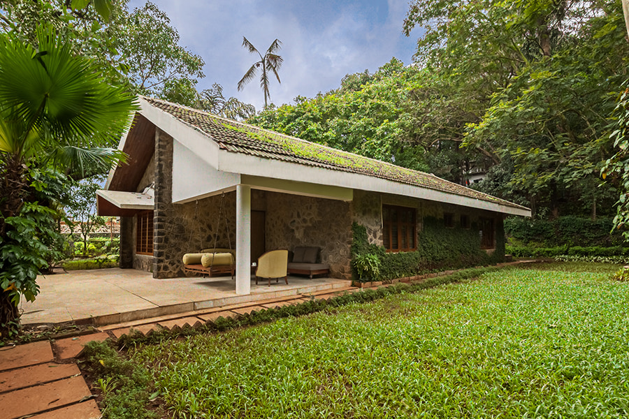 Stone house with roof, swing, front porch and green lawn where pets can play