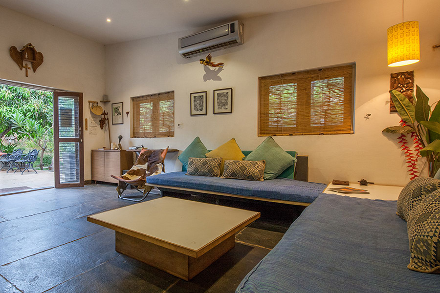 Living room with sofa, cushions, plants, coffee table and facing swimming pool