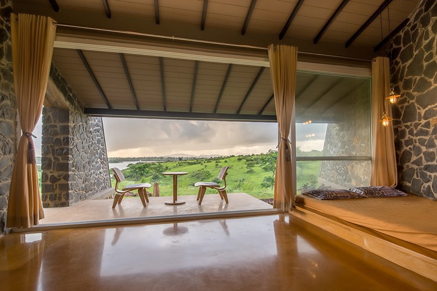 Spacious living room for pets, stone walls, front porch, tall open windows facing vast green lawn