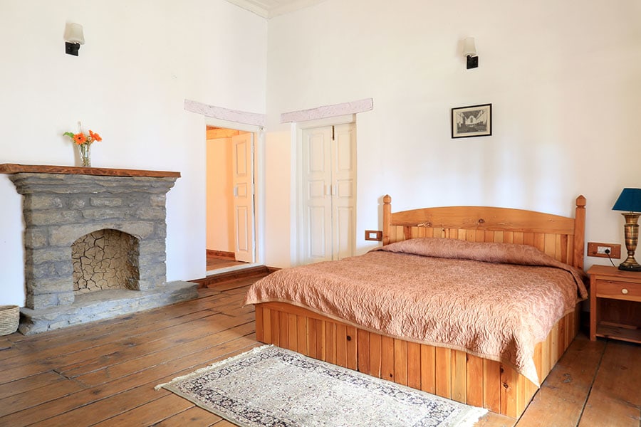 Spacious bedroom in Manali villa, bright interiors and fireplace