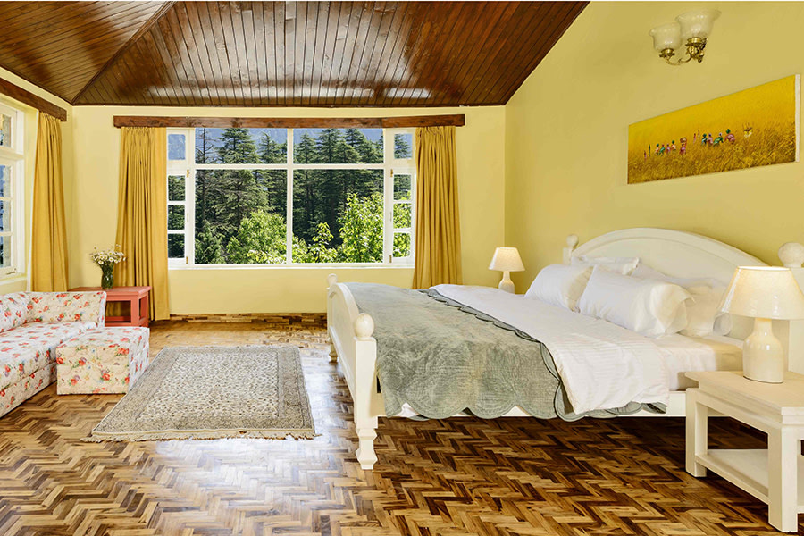 Cozy bedroom in Manali villa, wooden roof and floor, pastel yellow walls