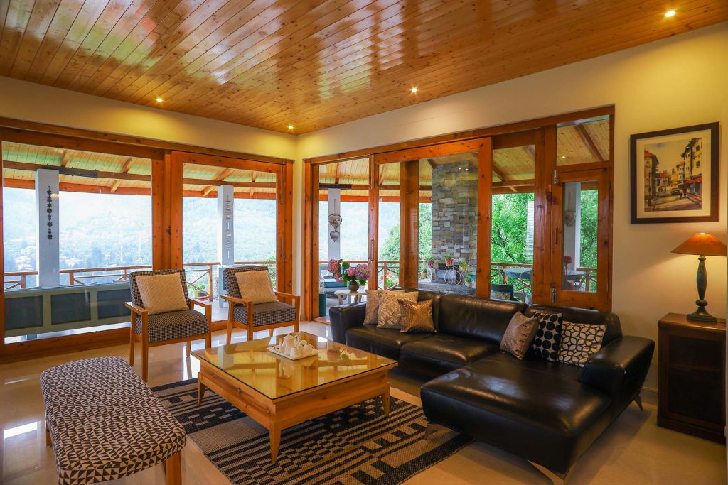 Spacious living room in Manali, modern furniture, tall windows, garden facing