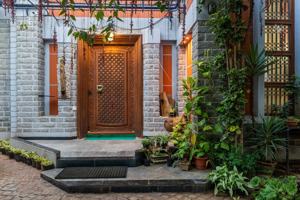 Beautiful entrance to villa in Bangalore, carved wooden front gate, house plants