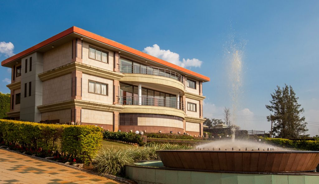 Massive palace structure with water fountain and lush lawn in a villa near Mumbai