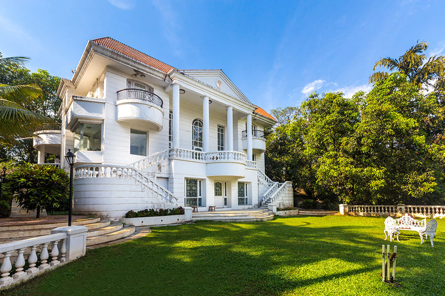 White palace structure with vast lawn in a villa near Mumbai