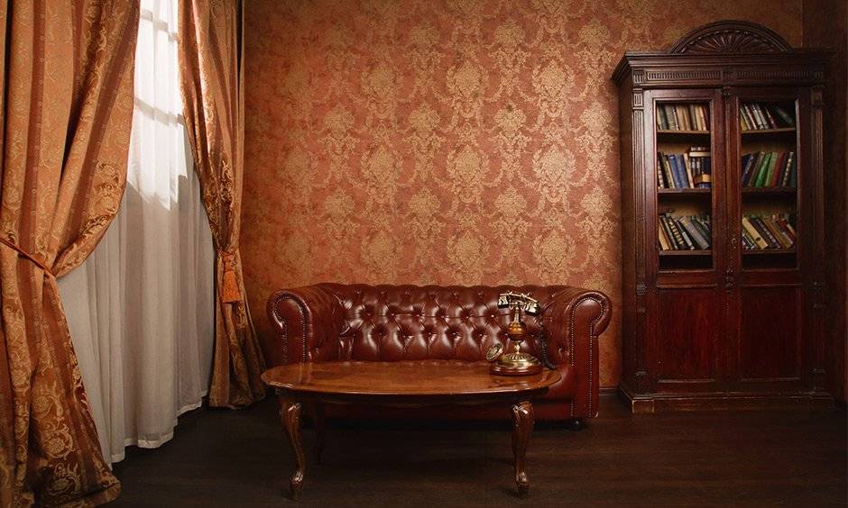 Brown gold wallpaper brings in old-world charm with elegant bookshelf and couch combined with other vintage furnishings