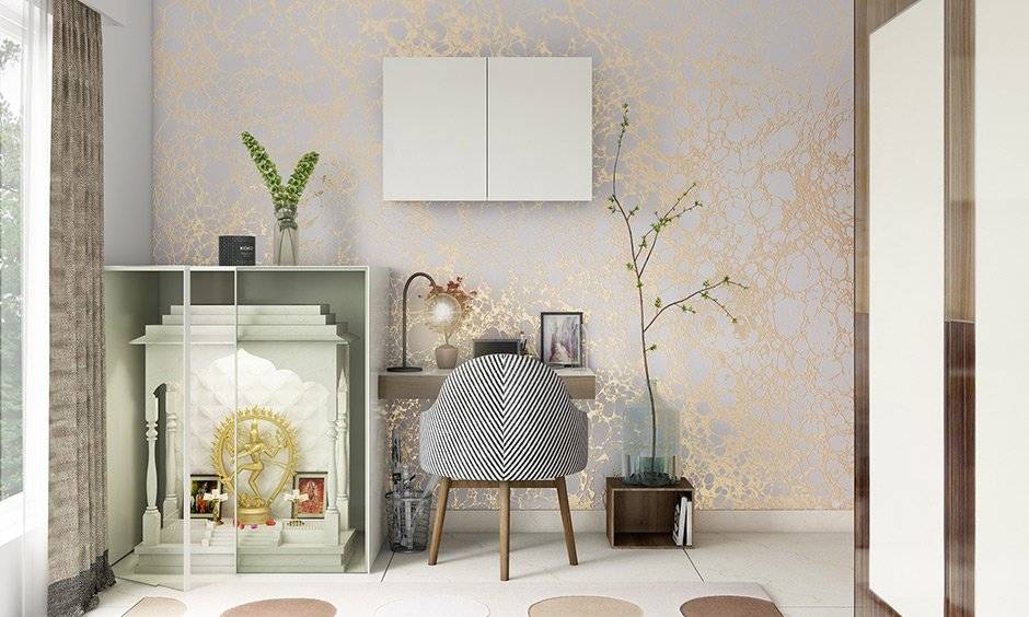 A pale white and gold wallpaper creates the right kind of aura around the pooja unit and study table