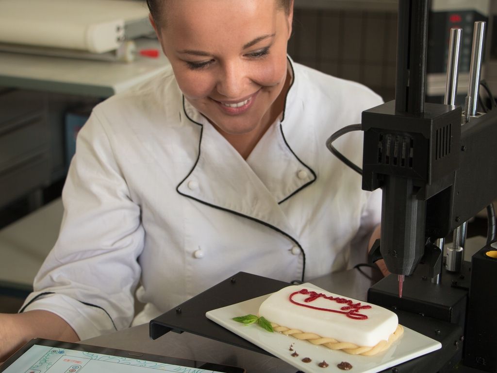 Chef looking at a pastry being printed by a 3D printer